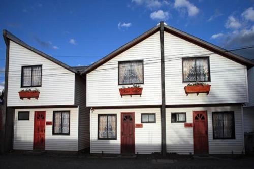 a white house with red doors and windows at Cabañas Última Esperanza in Puerto Natales