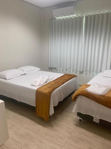 a bedroom with two beds and a window at Suites Paraíso de Minas in Capitólio