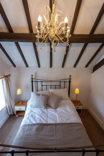 a bedroom with a large bed with a chandelier at Cliff House Holiday Cottages in Ebberston