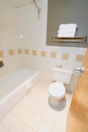 a bathroom with a white toilet and a bath tub at Canad Inns Destination Centre Fort Garry in Winnipeg