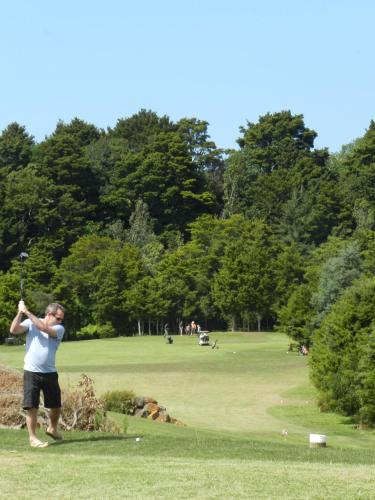 a man swinging a golf club in a park at Puketotara Lodge in Kerikeri