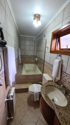 a bathroom with a toilet and a sink and a tub at Hotel Azaleia in Gramado