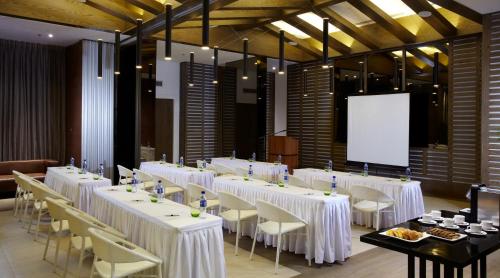 a conference room with white tables and chairs and a screen at Mövenpick Hotel Mactan Island Cebu in Mactan