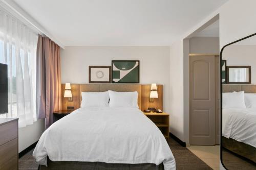 a bedroom with a large white bed and a television at Staybridge Suites - Atlanta NE - Duluth by IHG in Duluth