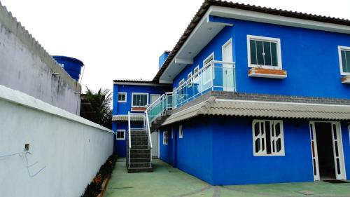 una casa azul con una escalera en el lateral de ella en Nacif&Alcantara Suítes, en Tamoios