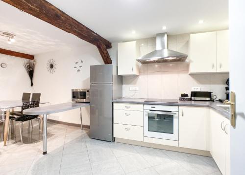 eine Küche mit einem Kühlschrank aus Edelstahl und einem Tisch in der Unterkunft Guesthouse Les 3 Chateaux in Eguisheim
