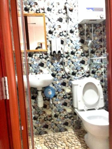 un bagno con un muro in pietra con un water e un lavandino di Marrigold Hostel a Hong Kong
