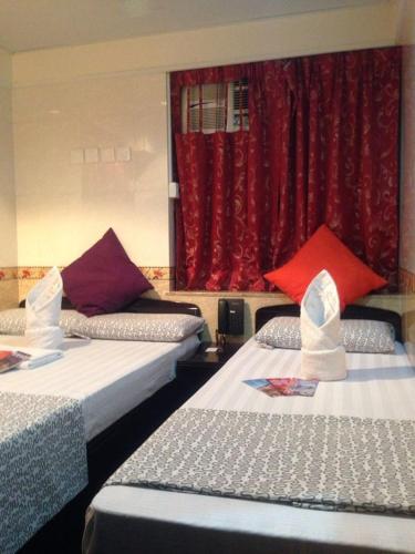 due letti in una stanza con una tenda rossa di Marrigold Hostel a Hong Kong