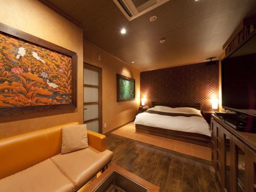 a bedroom with a bed and a couch and a tv at Hotel Grand Fine Kyoto Okazaki Heian Jingu Shrine in Kyoto