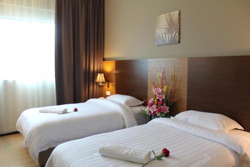 Dos camas en una habitación de hotel con flores. en Aroma Hotel en Butterworth
