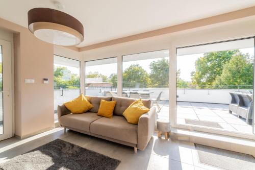 a living room with a couch and large windows at LAKE MOMENTS - Emerald Penthouse in Balatonszemes
