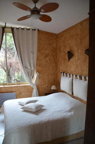 a bedroom with a white bed with a ceiling fan at Les Gîtes Les Mayombes in Roquebrune-sur-Argens