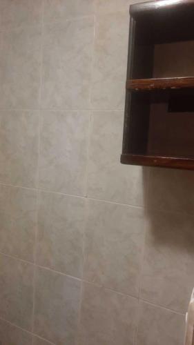 a bathroom with a tiled wall and a shelf at Flying Donkey in Otavalo