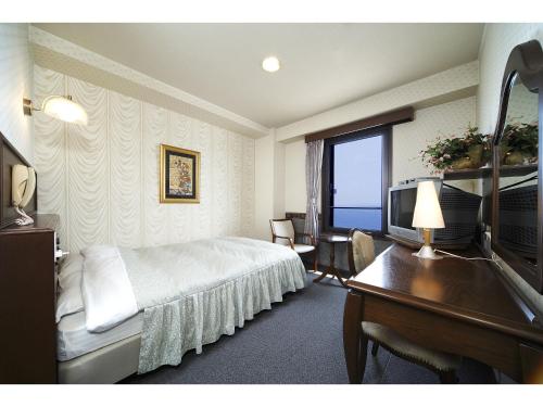 函館市にあるシーサイドホテルかもめのベッド、デスク、テレビが備わるホテルルームです。