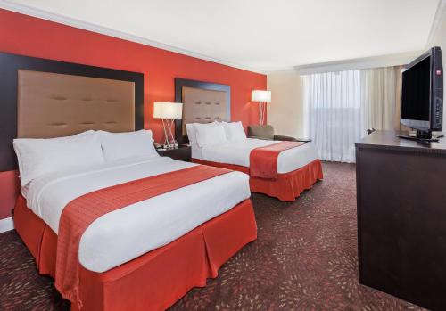 a hotel room with two beds and a flat screen tv at Holiday Inn Tyler - Conference Center, an IHG Hotel in Tyler