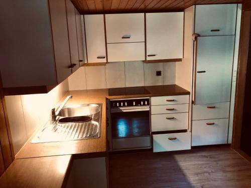 een keuken met witte kasten, een wastafel en een fornuis bij Gemütliches Zuhause mit Ausblick in Wilderswil
