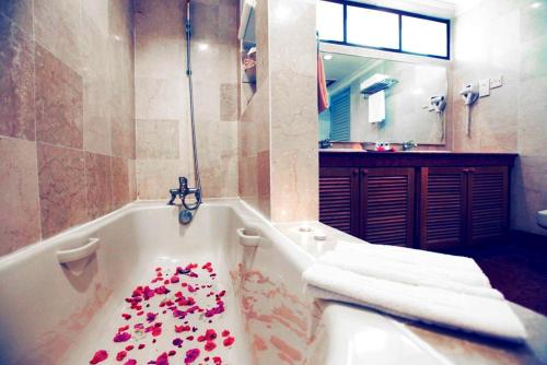 a bathroom with a tub filled with red roses at Sutra Beach Resort, Terengganu in Batu Rakit