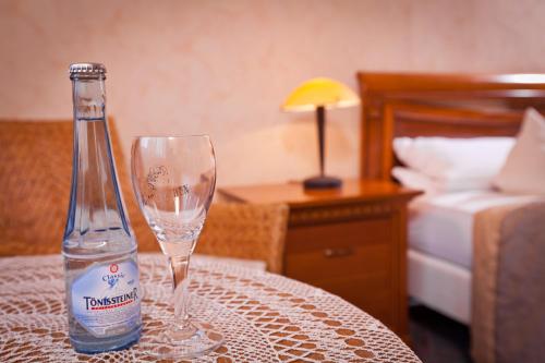 Una botella de agua sentada en una mesa con una copa de vino en Hotel Spies, en Gladenbach