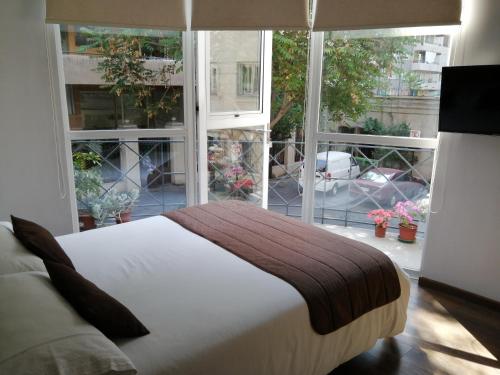 a bedroom with a bed and a large window at Hotel Elisa Cole in Santiago