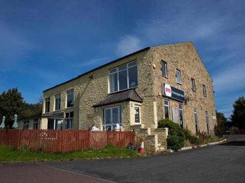 a brick building on the side of a street at OYO Knowesgate Inn, Northumberland National Park in Kirkwhelpington