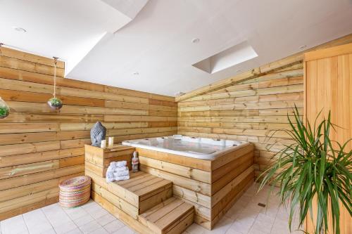 Le Comptoir des Ecoliers في Gémozac: حوض جاكوزي في غرفة مع جدران خشبية