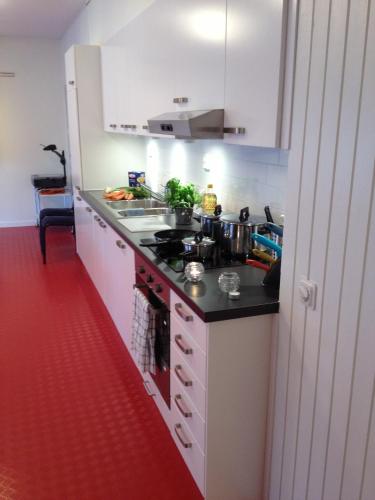 a kitchen with a stove and a red floor at Ariston Hotell in Lidingö
