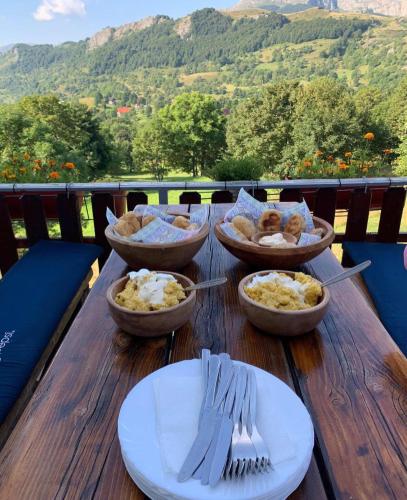 a wooden table with bowls of food and forks and plates at Konak Umoljani in Umoljani