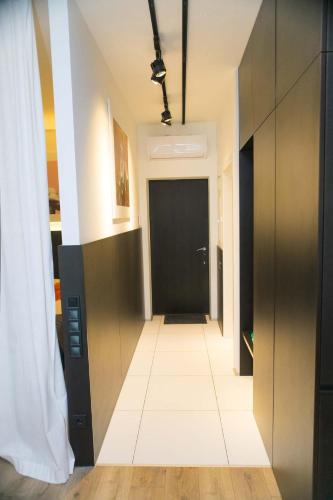 a hallway with a black door and a white tile floor at Stylish 1 bedroom studio near Most City in Dnipro