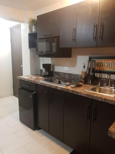 a kitchen with black cabinets and a sink and a microwave at Casa Cacho in Tijuana
