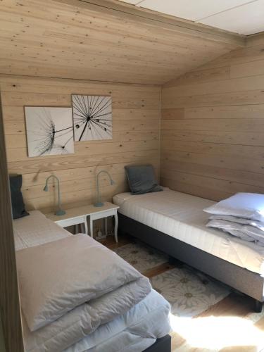 two beds in a room with wooden walls at Chalet Harmony in Zutendaal