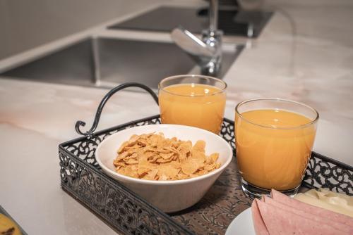 a tray with a bowl of cereal and two glasses of orange juice at Asteria Apartments in Meganisi