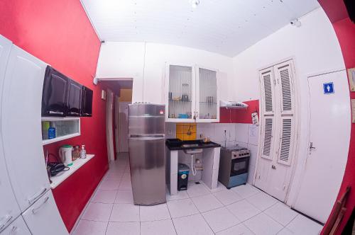 a kitchen with a refrigerator and a red wall at Hostel Dragão do Mar Fortaleza in Fortaleza
