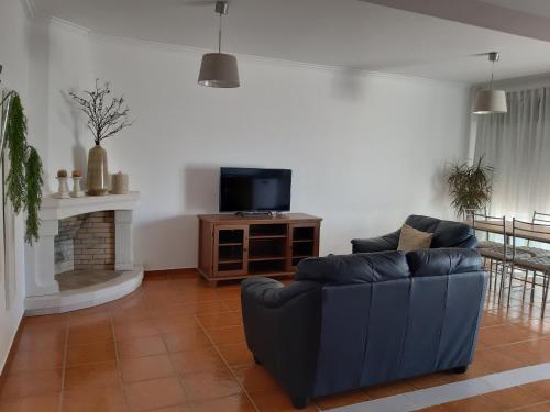 un soggiorno con un divano blu e una TV di Casa O'lado a Golegã