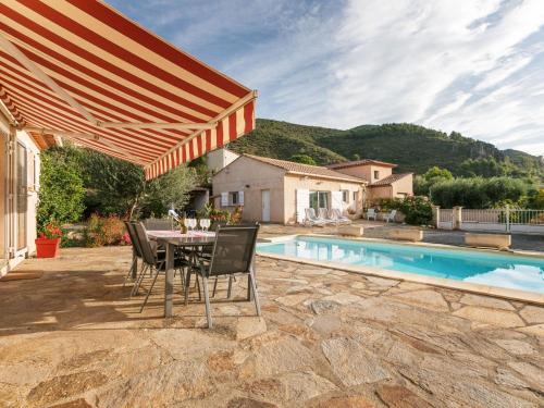 un patio con mesa, sillas y piscina en House in the south of France with private pool en Roquebrun