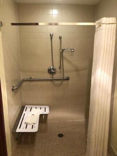 a bathroom with a shower with a bench in it at Super 8 by Wyndham Plover Stevens Point Area in Plover