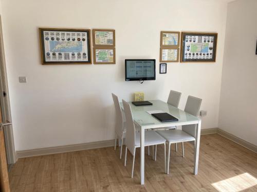 a white table with chairs and a tv on a wall at The Annex at Highmead in Exeter