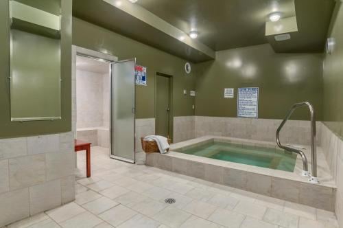La salle de bains est pourvue d'un bain à remous et d'une douche. dans l'établissement Super 8 by Wyndham Cochrane, à Cochrane