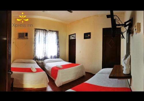 a room with three beds in it with a window at Xpress Inn Hotel in Veracruz