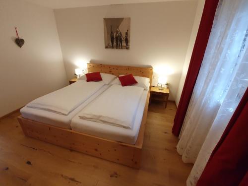 a bedroom with a bed with white sheets and red pillows at Apartment "Künstlhäusl" in Jochberg