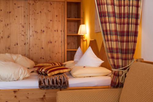 a bedroom with a bed with a curtain and a chair at Am Dorfplatz Suites - Adults friendly in Sankt Anton am Arlberg