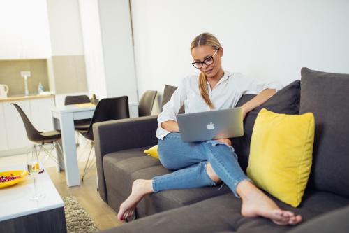 a woman sitting on a couch with a laptop at LUST PREMIUM Apartments in Kragujevac