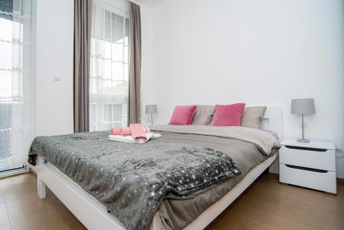 a bedroom with a large bed with pink pillows on it at LUST PREMIUM Apartments in Kragujevac