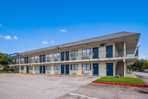 an apartment building with blue doors and a parking lot at Motel 6-College Station, TX - Bryan in College Station