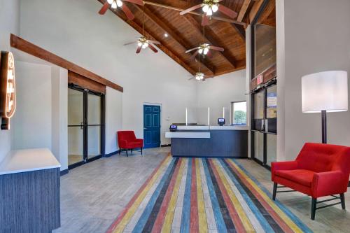 an office lobby with two red chairs and a desk at Studio 6-Jacksonville, FL - Baymeadows in Jacksonville
