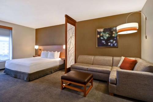 Habitación de hotel con cama y sofá en Hyatt Place Huntsville - Research Park - Redstone en Huntsville