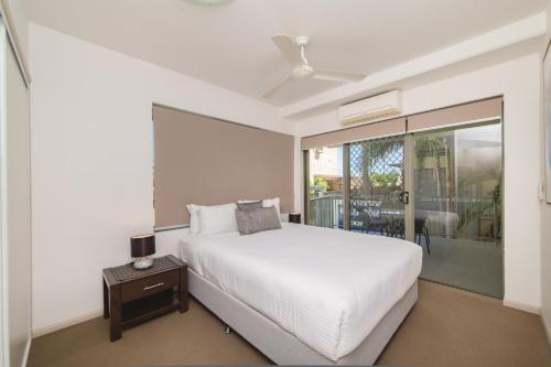 a bedroom with a white bed and a balcony at Beaches on Lammermoor Apartments in Yeppoon