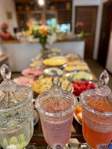 a table topped with different colored drinks in glass containers at Pousada João Sol in Praia do Forte