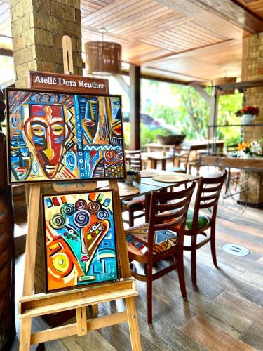 a painting on a stand with chairs and a table at Pousada João Sol in Praia do Forte