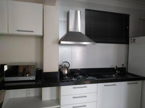 une petite cuisine avec une cuisinière et un micro-ondes dans l'établissement Vivendas Summer Beach Apto Particular, à Bombinhas