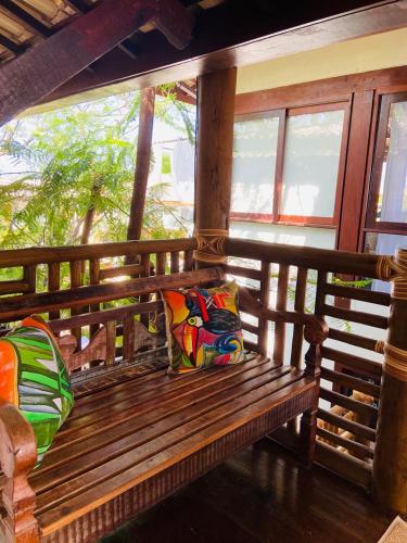 a wooden bench with two pillows on a porch at Pousada João Sol in Praia do Forte